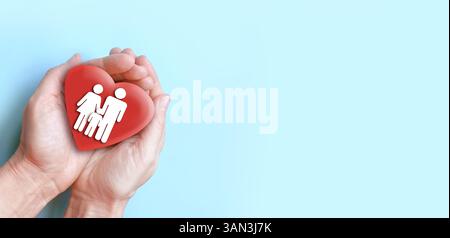 Familie und Herz in Händen über blauem Hintergrund. Liebes- und Familienkonzept. Stockfoto