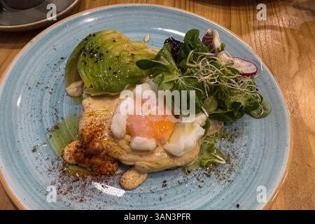 Gesunder Toast mit pochiertem Ei und Avocado auf dem Restauranttisch Stockfoto
