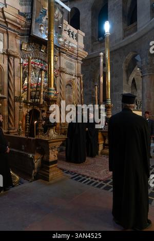 Griechisch-orthodoxe Geistliche stehen am Eingang der Rotunde Edicule oder Anastasia, die die Engelskapelle enthält, eine Vorkammer, die zum Grab Jesu Christi führt, in der Kirche des Heiligen Grabes in der Altstadt von Jerusalem, Israel. Stockfoto