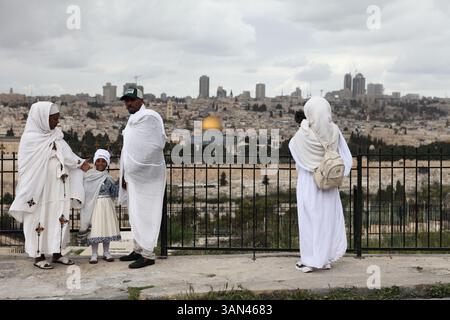 Äthiopische christliche Familie, Pilger in weiß, die mit der Felsenkuppel im Rücken fotografiert werden, bevor sie in einer Palmensonntagsprozession laufen. Stockfoto
