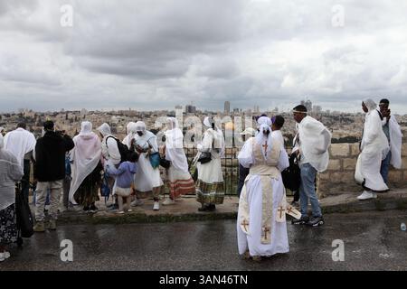 Äthiopische Christen, vor allem Frauen, die weiße Frauen tragen, mischen sich, bevor sie in eine Palmensonntagsprozession auf dem Ölberg, dem Felsendom, der hinten gesehen wird, gehen. Stockfoto