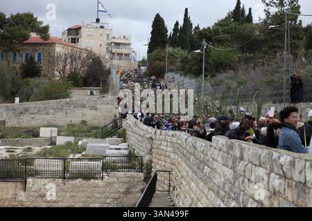 Christliche Pilger in der ganzen Welt singen und beten, während sie auf dem Mt. Oliven in einer Palmensonntagsprozession mit Palmenwedel und Olivenbaumzweigen. Stockfoto