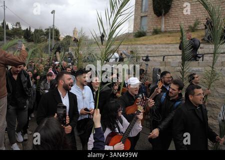 Christliche Pilger in der ganzen Welt singen und beten, während sie auf dem Mt. Oliven in einer Palmensonntagsprozession mit Palmenwedel und Olivenbaumzweigen. Stockfoto