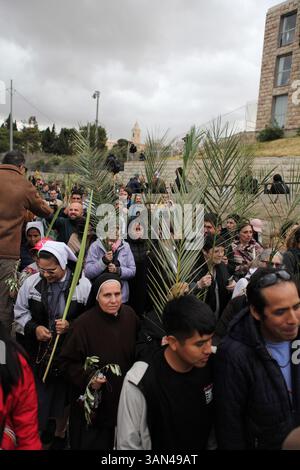 Christliche Pilger in der ganzen Welt singen und beten, während sie auf dem Mt. Oliven in einer Palmensonntagsprozession mit Palmenwedel und Olivenbaumzweigen. Stockfoto