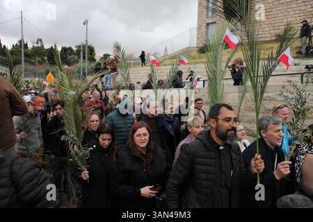 Christliche Pilger in der ganzen Welt singen und beten, während sie auf dem Mt. Oliven in einer Palmensonntagsprozession mit Palmenwedel und Olivenbaumzweigen. Stockfoto
