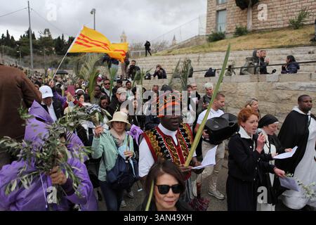 Christliche Pilger in der ganzen Welt singen und beten, während sie auf dem Mt. Oliven in einer Palmensonntagsprozession mit Palmenwedel und Olivenbaumzweigen. Stockfoto