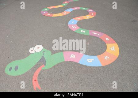Schlange mit Buchstaben des Alphabets gemalt auf Schulspielplatz Asphalt Oberflächenkonzept Alphabetisierung Lesen der Grundschulkindschule Stockfoto