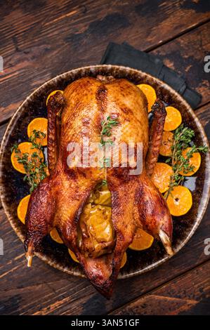 Gänse mit Äpfeln und Orangen auf Teller mit Kräutern braten. Hölzerner Hintergrund. Draufsicht Stockfoto