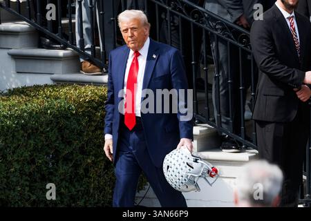 Washington, Usa. April 2025. Präsident Donald Trump hält einen Fußballhelm, als er am Montag, den 14. April 2025 auf dem Südrasen des Weißen Hauses in Washington D.C. eine Veranstaltung mit dem Gewinnerteam der College Football Championship 2025, der Ohio State University, abreist. (Foto: Aaron Schwartz/SIPA USA) Credit: SIPA USA/Alamy Live News Stockfoto