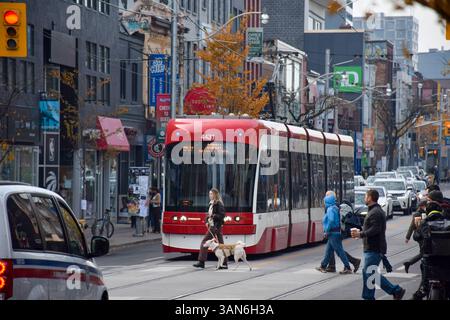 30. Oktober 2022: Toronto, Ontario, Kanada: Fußgänger überqueren die Queen Street vor der roten Straßenbahn in Toronto Stockfoto