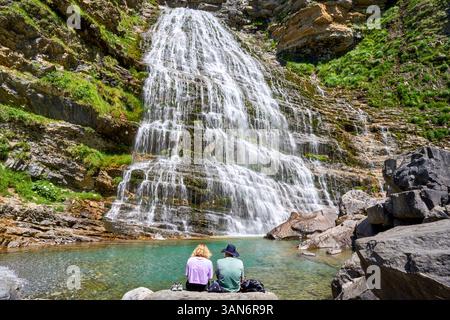 Ein Paar im Ordesa-Tal, das den spektakulären Wasserfall Cola de Caballo in Pyrenäen, Spanien, betrachtet. Stockfoto