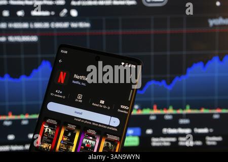 Dhaka, Bangladesch 08. März 2025: Installationsbildschirm der Netflix-App auf einem Smartphone und die Finanzmarktkarte im Hintergrund Stockfoto