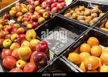 Obsttheke in einem Supermarkt oder Bio-Lebensmittelgeschäft, hier mit verschiedenen Arten von Äpfeln, Kiwis, Orangen und einem leeren Abteil für Birnen Stockfoto