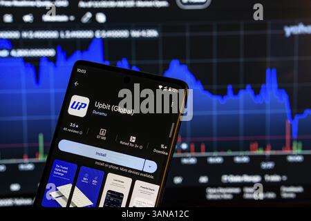 Dhaka, Bangladesch 08. März 2025: Installationsbildschirm der UPbit-App auf einem Smartphone und die Finanzmarktkarte im Hintergrund Stockfoto