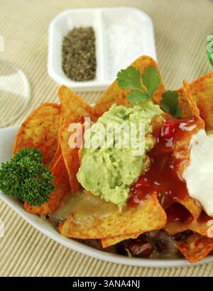 Köstliche vegetarische Nachos mit Guacamole, Tomatensalsa und Sauerrahm Stockfoto