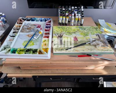 Kunstpult eines Aquarellkünstlers, der Farbröhren, eine Palette, Pinsel und ein unvollendetes Aquarellgemälde zeigt. USA Stockfoto