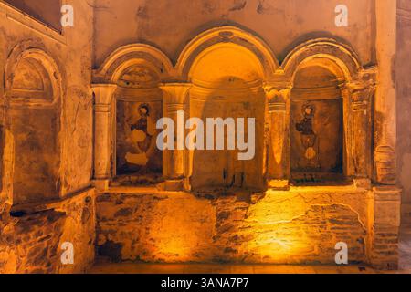 Im Inneren der St. John the Baptist Church in Sirince, Selcuk, Türkei, zieren historische Fresken die Wand, die von warmem Licht beleuchtet werden und komplizierte religiöse Kunst zeigen Stockfoto