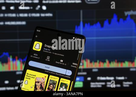 Dhaka, Bangladesch 08. März 2025: Installationsbildschirm der Snapchat-App auf einem Smartphone und die Finanzmarktkarte im Hintergrund Stockfoto