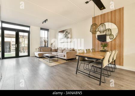 Geräumiges, modernes Wohnzimmer mit komfortablem Sofa, Esstisch und stilvollem Dekor, das Komfort und Eleganz in einem einladenden Raum vereint. Stockfoto