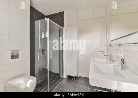 Stilvolles, modernes Bad mit eleganter Glasdusche, modernen Waschbecken und minimalistischer Einrichtung. Das Design betont Sauberkeit und Funktionalität. Stockfoto