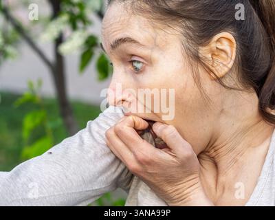 Eine Nahaufnahme einer Hirschzecke, die am Arm einer Person herumkriecht. Die Arachnide ist rötlich gefärbt und hat ihre Beine als Kriechen ausgestreckt Stockfoto