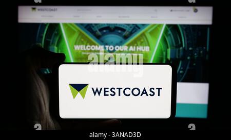 In dieser Abbildung hält eine Person ein Mobiltelefon mit dem Logo des britischen IT-Unternehmens Westcoast Limited auf dem Bildschirm vor der Webseite. Stockfoto