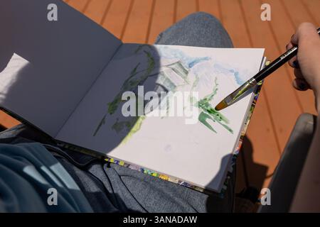Der Künstler malt mit Aquarellfarben in einem Skizzenbuch Stockfoto