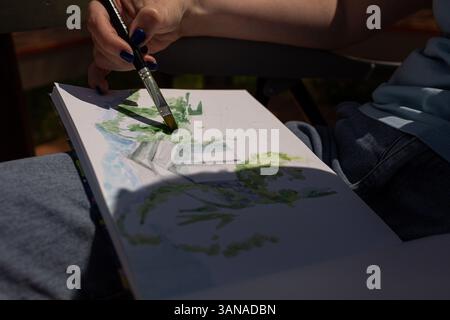 Der Künstler malt mit Aquarellfarben in einem Skizzenbuch Stockfoto
