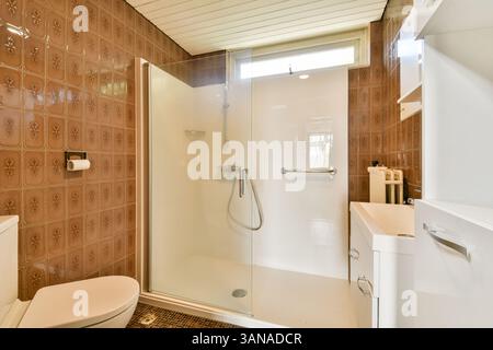 Ein elegantes und modernes Duschbad mit Glasgehäuse, stilvollen Fliesen und organisiertem Schrank schafft eine frische und einladende Atmosphäre. Stockfoto