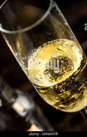 Goldfarbenes Champagnerglas mit Blasen auf dunklem Hintergrund Stockfoto