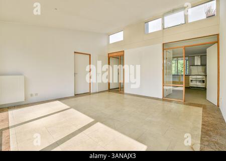 Geräumiger, minimalistischer Raum mit viel Tageslicht, schlichter Architektur und dezenter Farbpalette. Ideal für modernes Wohnen. Stockfoto