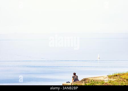 Allein sitzender Mann, der auf das Meer bis zum Horizont blickt Stockfoto