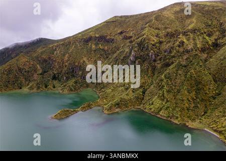 Blick aus der Vogelperspektive auf die Lagoa do Fogo, umgeben von üppigen Bergen und unberührtem Wasser, Ribeira Grande, Portugal. Stockfoto