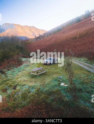 Accous, Frankreich - 15. November 2024: Aus der Vogelperspektive eine ruhige und nebelige Morgenlandschaft mit Straße und Auto inmitten der ruhigen Berge und Hügel, Stockfoto