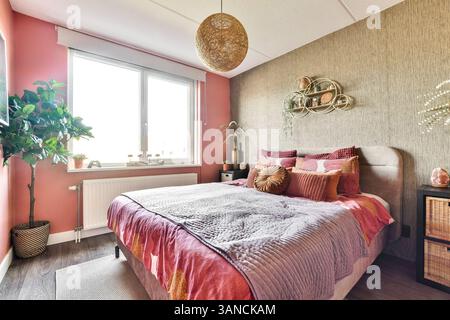 Ein wunderschön gestaltetes, modernes Schlafzimmer mit weichen Texturen, lebhaften Farben und einer Mischung aus natürlichen Elementen. Warmes Licht verstärkt die einladende Atmosphäre. Stockfoto