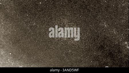 Dunkle, körnige Textur schafft einen abstrakten Hintergrund mit Vignetteneffekt Stockfoto