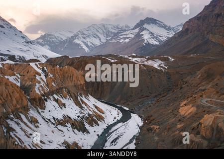 Aus der Vogelperspektive des Spiti Flusses, der bei Sonnenuntergang durch die schneebedeckten Berge in der Nähe der Gemeinde KAZA fließt, Himachal Pradesh, Indien. Stockfoto