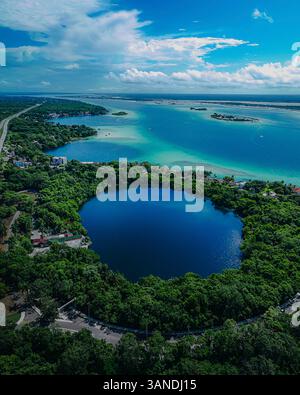 Blick aus der Vogelperspektive auf die ruhige Lagune von Xenote Azul, umgeben von üppigem Wald und klarem blauem Wasser, Bacalar, Quintana Roo, Mexiko. Stockfoto