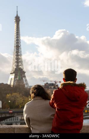 Ein Paar, das den Eiffelturm in Paris bewundert. Romantischer Blick auf die Stadt unter bewölktem Himmel. Reisen Sie in Frankreich. Stockfoto
