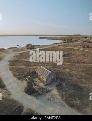 Aus der Vogelperspektive auf etang de Canet et de Saint-Nazaire mit rustikalen Fischerhütten und ruhigem Wasser, Canet-en-Roussillon, Frankreich. Stockfoto