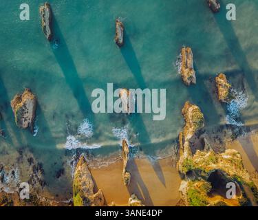 Aus der Vogelperspektive auf das türkisfarbene Meer und die felsigen Klippen in Praia de Boiao, Faro, Portugal. Stockfoto