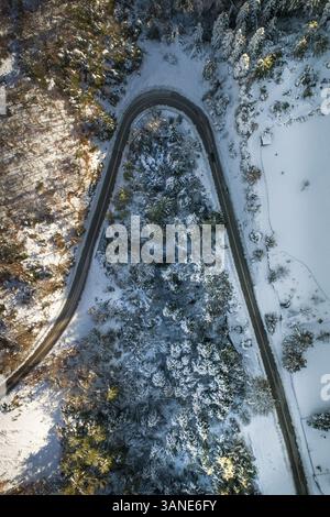Aus der Vogelperspektive auf eine leere Straße, umgeben von Schnee Stockfoto
