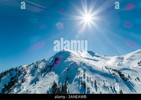 Blick aus der Vogelperspektive auf die Sonne, die über den schneebedeckten Gebirgszug des Erymanthos scheint, Griechenland Stockfoto