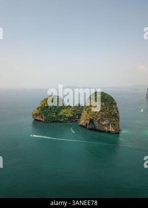 Aus der Vogelperspektive winzige Schnellboote erkunden die riesigen Kalksteinklippen und Inseln im türkisblauen Meer, einem tropischen Paradies, Phra Nang, Krabi, Phu Stockfoto