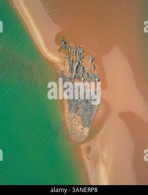 Aus der Vogelperspektive auf den Nullagine River, der durch eine wunderschöne Küstenlandschaft mit Sandstrand und blauem Ozean fließt, Cossack, Australien. Stockfoto