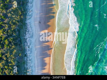 Blick von der Drohne auf den Tallows Beach in der Nähe des Byron Bay Lighthouse bei Sonnenuntergang, im Bundesstaat New South Wales Australien. Der Schatten der Bäume spiegelt sich auf dem Th Stockfoto