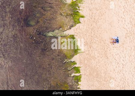 Aus der Vogelperspektive eines Paares, das bei Ebbe am Balangan Beach in Bali, Indonesien lag. Stockfoto