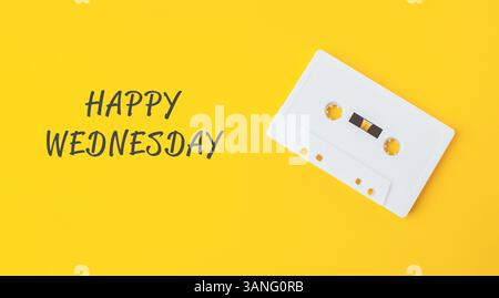 Weißes Kassettenband ist auf gelbem Hintergrund mit den Worten Happy Wednesday darunter. Nostalgiekonzept und eine Erinnerung, das einfache zu genießen Stockfoto