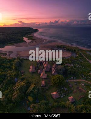 Blick aus der Vogelperspektive auf ein traditionelles Dorf mit Dächern und Häusern bei Sonnenaufgang am ruhigen Meer, Ratenggaro, Sumba, Indonesien. Stockfoto