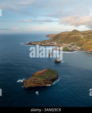 Luftaufnahme der Küstenstadt Mosteiros mit Meer, Felsformationen und Bergen, Insel Sao Miguel, Portugal. Stockfoto